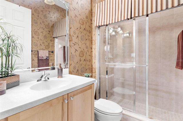 bathroom featuring a shower with shower door, vanity, and toilet