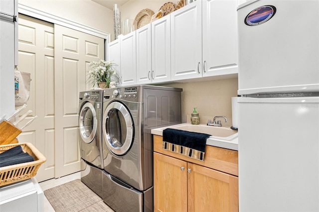 washroom featuring washing machine and dryer, cabinets, and light tile floors