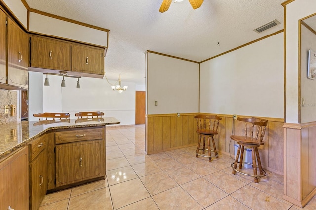 kitchen featuring ceiling fan with notable chandelier, light tile floors, dark stone counters, and a textured ceiling