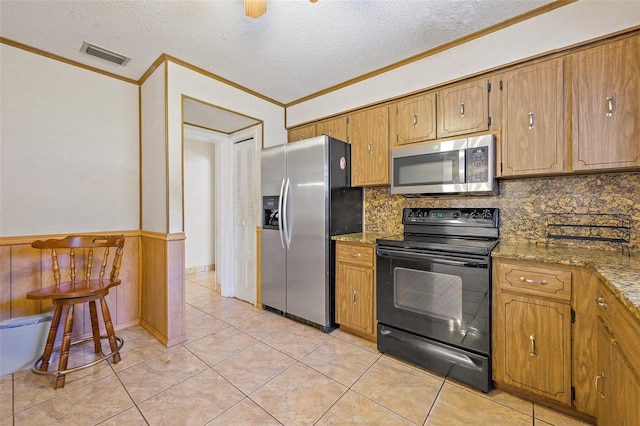 kitchen featuring backsplash, stainless steel appliances, light tile floors, dark stone counters, and a textured ceiling