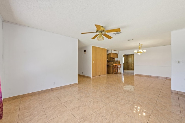 empty room with ceiling fan with notable chandelier, a textured ceiling, and light tile floors