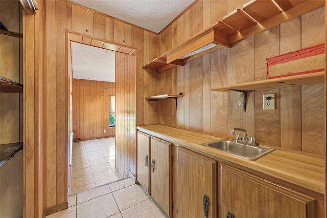 kitchen with wood walls, a textured ceiling, and sink