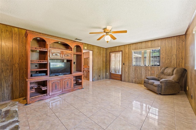 living room featuring ceiling fan, wooden walls, and light tile floors