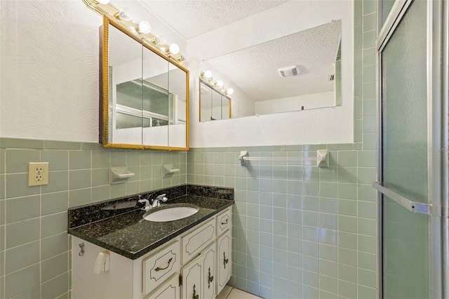 bathroom featuring vanity, tasteful backsplash, tile walls, and a textured ceiling