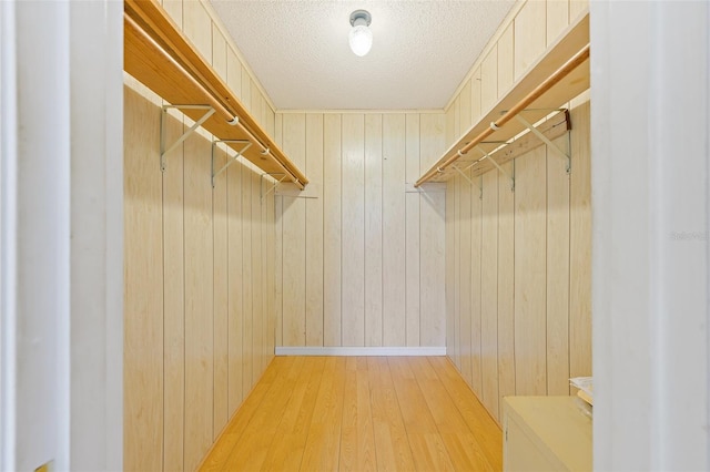 walk in closet with light hardwood / wood-style floors