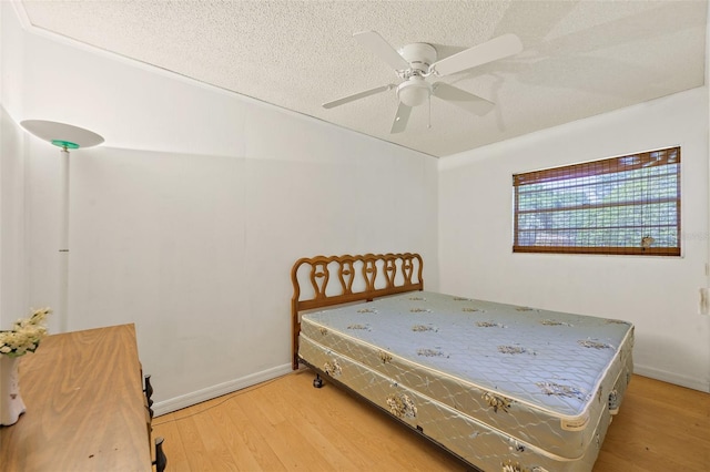 bedroom with light hardwood / wood-style flooring, ceiling fan, and a textured ceiling