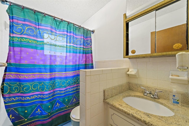 bathroom with vanity with extensive cabinet space, tile walls, a textured ceiling, backsplash, and toilet