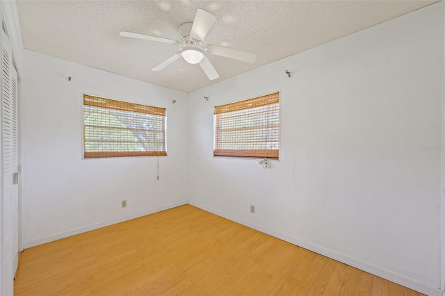 empty room with ceiling fan, a textured ceiling, and light wood-type flooring