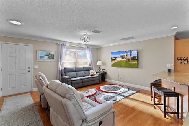 living room with a textured ceiling, ornamental molding, and light wood-type flooring