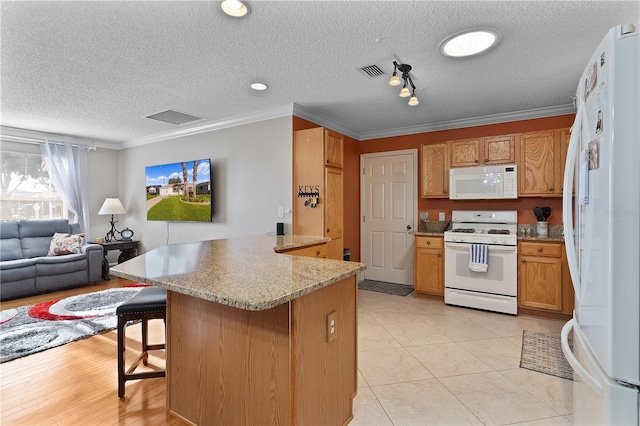 kitchen with white appliances, a kitchen bar, a textured ceiling, crown molding, and rail lighting