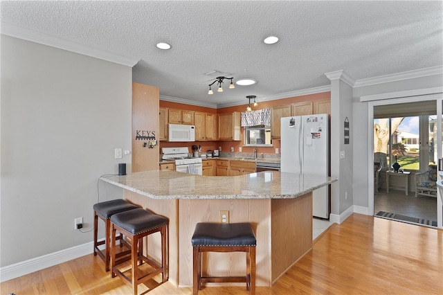 kitchen with light hardwood / wood-style floors, white appliances, and a breakfast bar