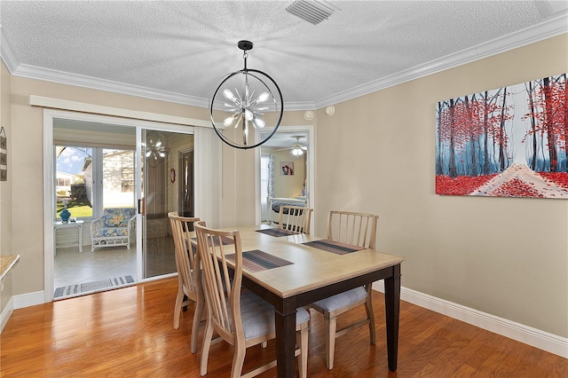 dining area with a textured ceiling, crown molding, ceiling fan with notable chandelier, and light wood-type flooring