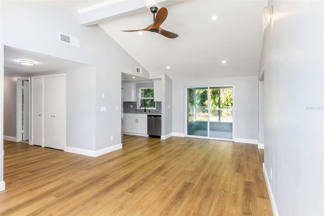 unfurnished living room with ceiling fan, high vaulted ceiling, beam ceiling, and light hardwood / wood-style floors