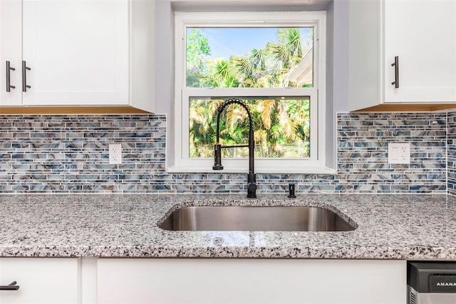 kitchen with white cabinetry, sink, and light stone counters