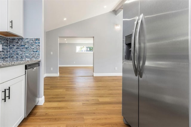 kitchen featuring tasteful backsplash, white cabinetry, appliances with stainless steel finishes, and vaulted ceiling with beams