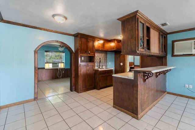 kitchen with a breakfast bar, crown molding, kitchen peninsula, ceiling fan, and light tile flooring