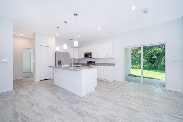 kitchen featuring decorative light fixtures, white cabinetry, appliances with stainless steel finishes, light tile floors, and a center island with sink