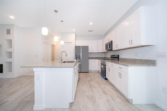 kitchen with hanging light fixtures, white cabinetry, appliances with stainless steel finishes, sink, and an island with sink