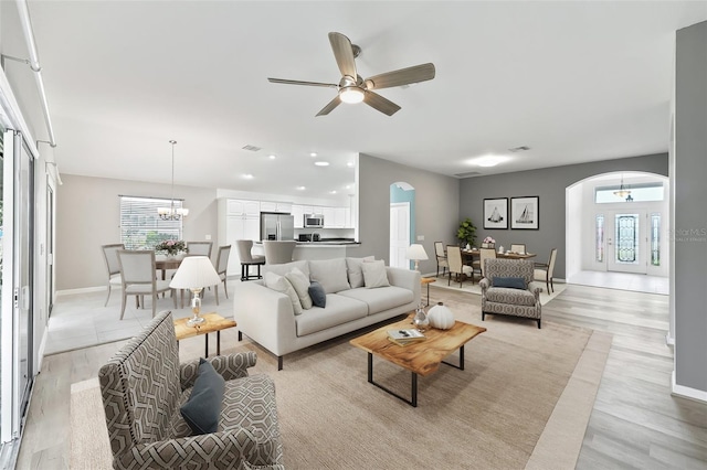 living room with light hardwood / wood-style floors and ceiling fan with notable chandelier