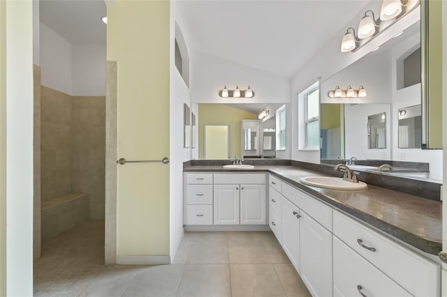 bathroom with lofted ceiling, tile floors, vanity with extensive cabinet space, and dual sinks