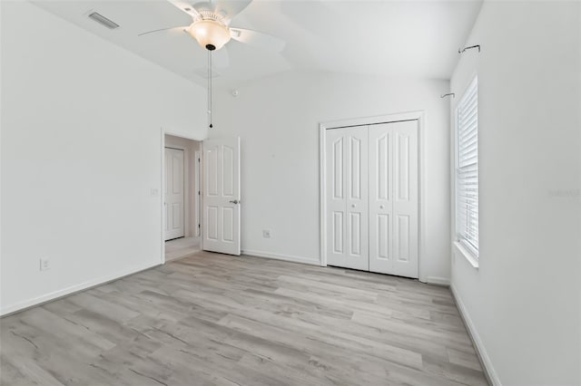 unfurnished bedroom featuring lofted ceiling, light hardwood / wood-style flooring, ceiling fan, and a closet