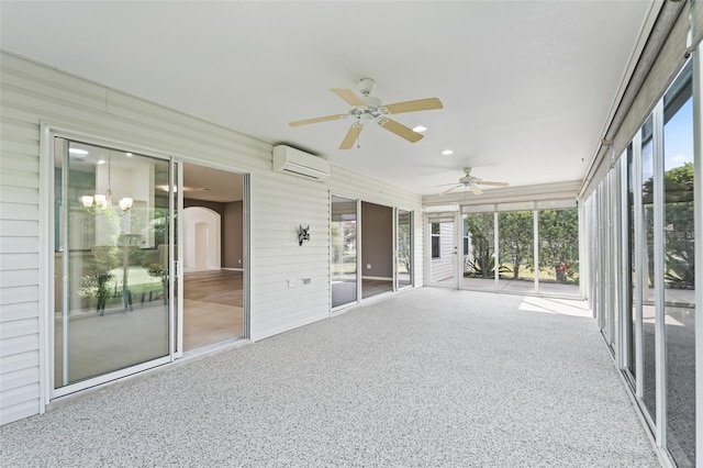 unfurnished sunroom featuring ceiling fan with notable chandelier and an AC wall unit