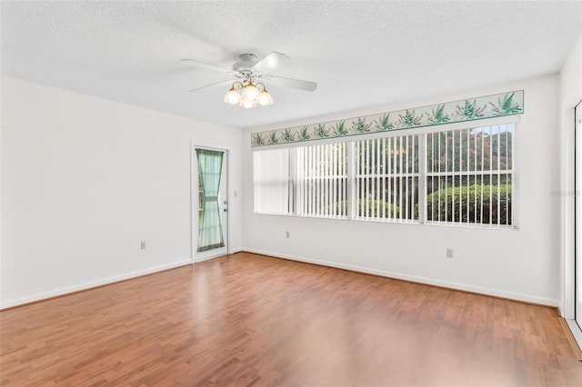 unfurnished room with ceiling fan, a healthy amount of sunlight, a textured ceiling, and hardwood / wood-style flooring