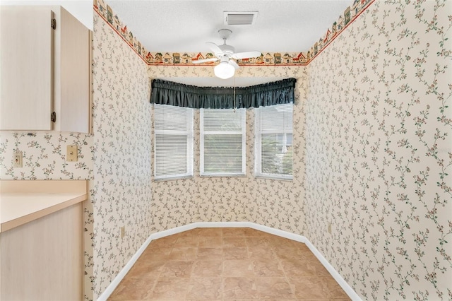 unfurnished dining area with a textured ceiling and ceiling fan