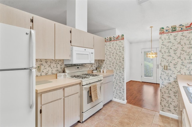 kitchen with white appliances, hanging light fixtures, light tile patterned floors, light brown cabinetry, and a chandelier