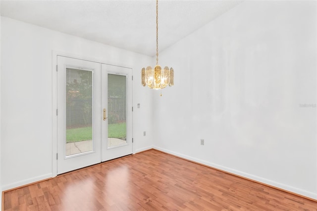 unfurnished dining area with wood-type flooring, french doors, and an inviting chandelier