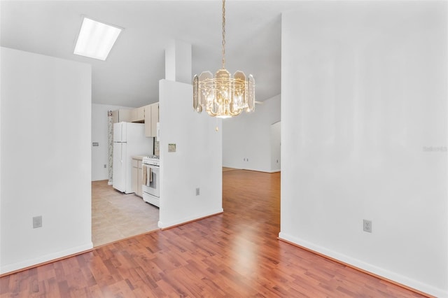 unfurnished dining area with a chandelier, light wood-type flooring, and vaulted ceiling