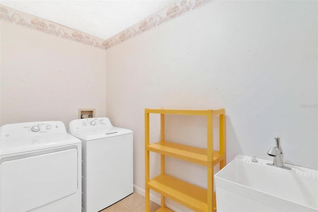 clothes washing area featuring light tile patterned flooring, independent washer and dryer, and sink