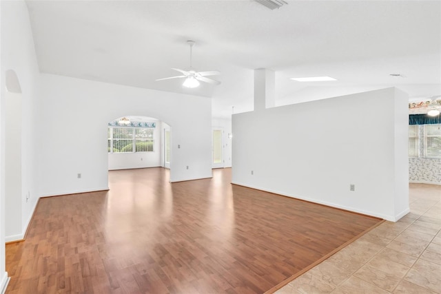 unfurnished living room with ceiling fan, lofted ceiling, and light wood-type flooring