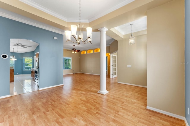 spare room with decorative columns, light tile flooring, ceiling fan with notable chandelier, and a tray ceiling