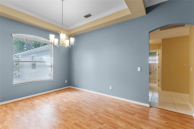 unfurnished room featuring a raised ceiling, light hardwood / wood-style floors, and a chandelier