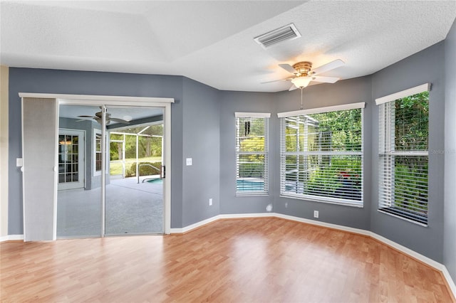 empty room featuring ceiling fan, light wood-type flooring, and a textured ceiling