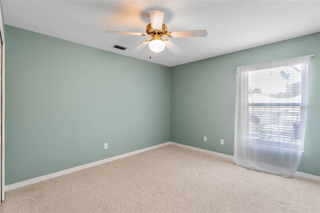 spare room with a textured ceiling, ceiling fan, and light carpet