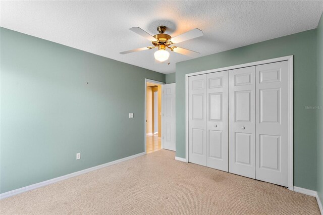 unfurnished bedroom with light colored carpet, a textured ceiling, ceiling fan, and a closet