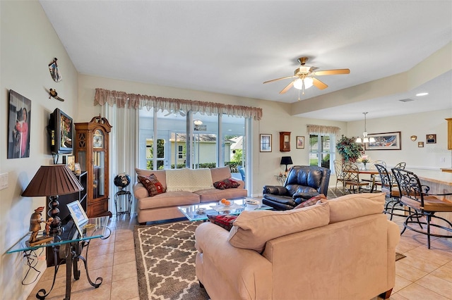 tiled living room with ceiling fan with notable chandelier