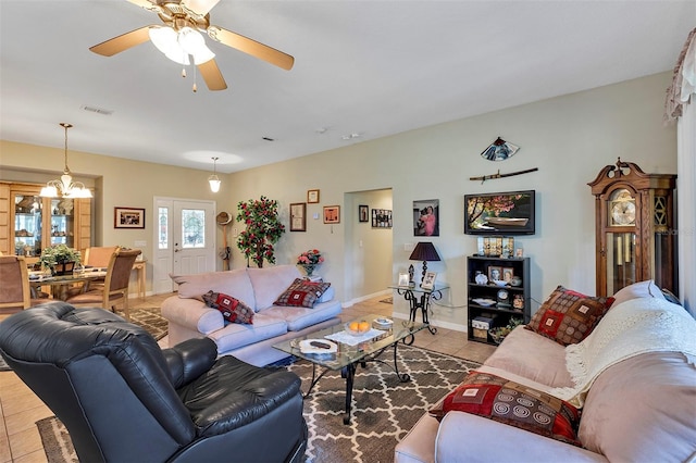 living room with ceiling fan with notable chandelier and light tile floors