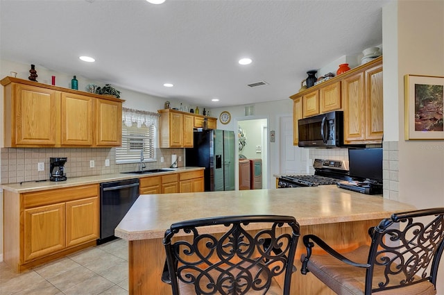 kitchen with sink, tasteful backsplash, black appliances, and a breakfast bar