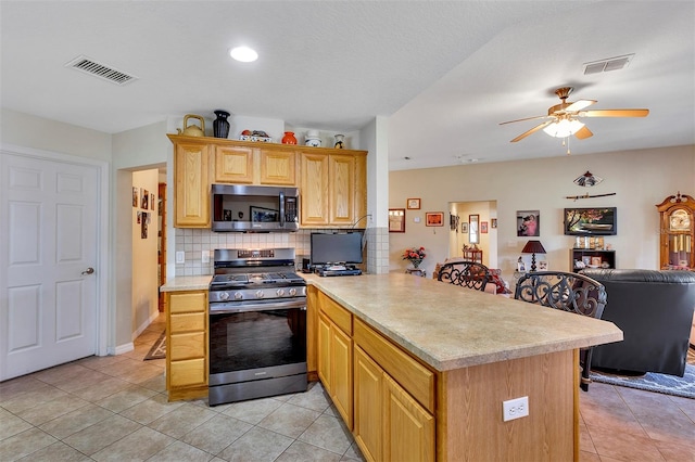 kitchen with tasteful backsplash, light tile floors, range with gas cooktop, ceiling fan, and a textured ceiling