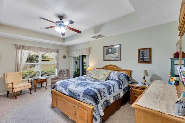 bedroom featuring light colored carpet, ceiling fan, and a tray ceiling