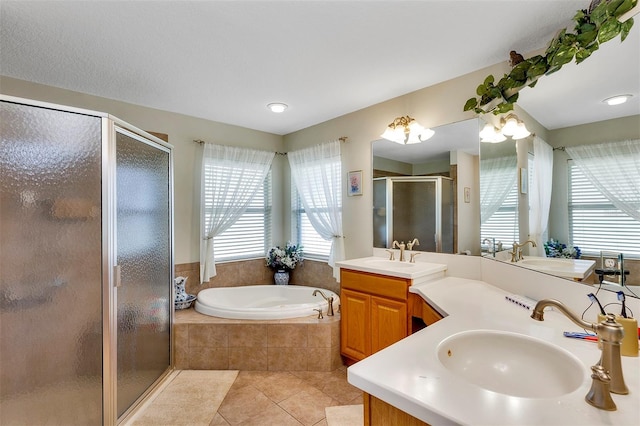 bathroom with tile flooring, independent shower and bath, double sink vanity, and a wealth of natural light