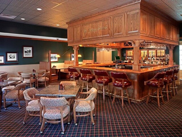 bar with light stone countertops and dark colored carpet