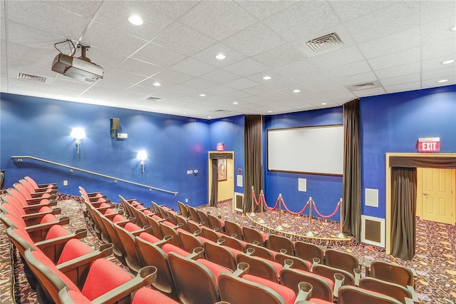 carpeted cinema room with a paneled ceiling