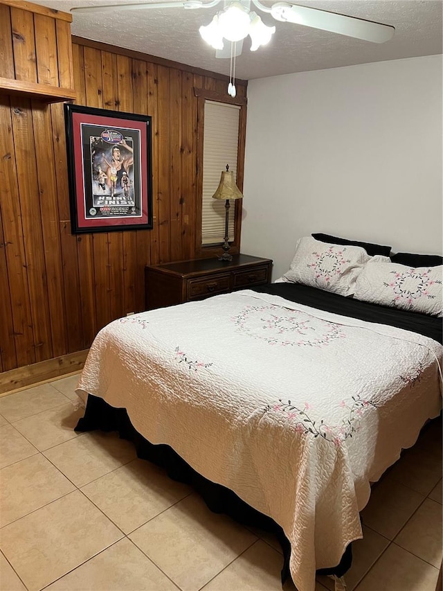 tiled bedroom with wooden walls, ceiling fan, and a textured ceiling