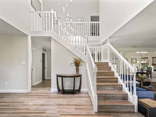 stairway featuring light hardwood / wood-style floors and a towering ceiling