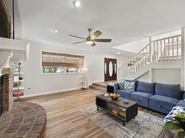 living room featuring light hardwood / wood-style floors, a brick fireplace, and ceiling fan