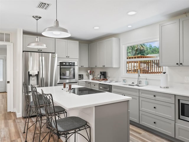 kitchen featuring appliances with stainless steel finishes, a kitchen breakfast bar, sink, and light hardwood / wood-style floors